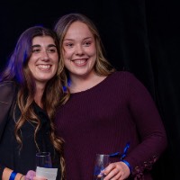 Girl in black shirt and girl in maroon shirt take a picture together